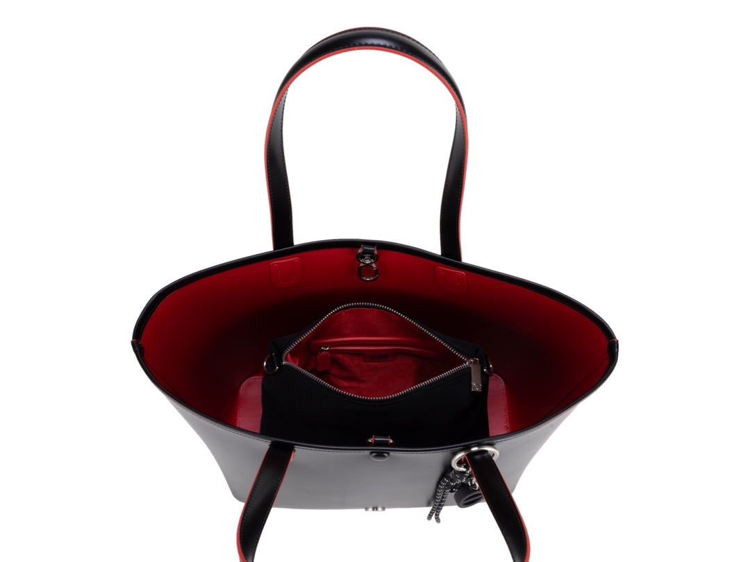 Bolsa tote color negro con bordes rojos y accesorio de borla decorativa, marca Cloe.
