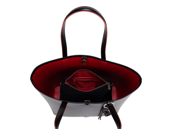 Bolsa tote color negro con bordes rojos y accesorio de borla decorativa, marca Cloe.