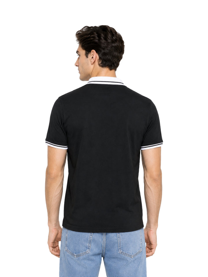 Hombre vistiendo playera polo color negro con detalles blancos en el cuello y los bordes de las mangas.