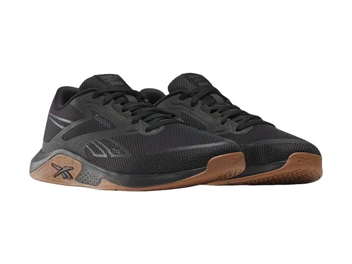 Tenis deportivos Reebok color negro con suela marrón, vista lateral.