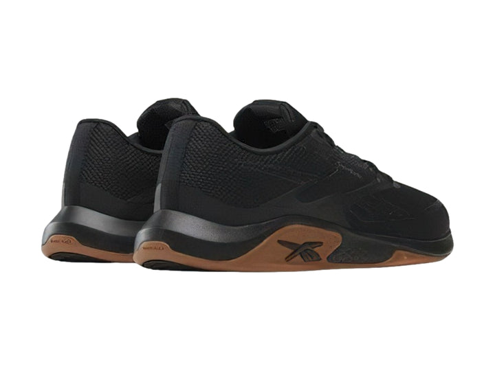 Tenis deportivos Reebok color negro con suela marrón, vista lateral.