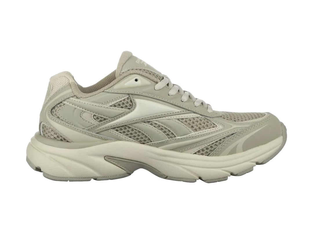 Tenis deportivos Reebok color beige con paneles de malla y suela robusta.