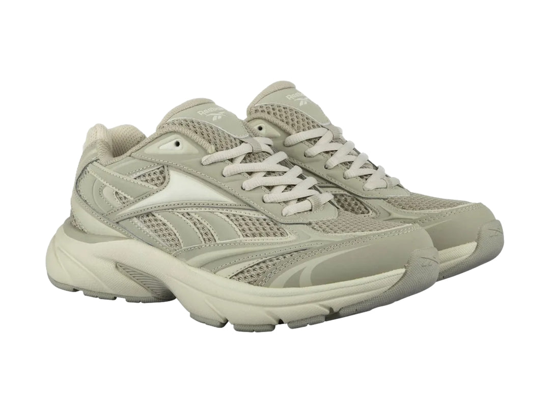 Tenis deportivos Reebok color beige con paneles de malla y suela robusta.