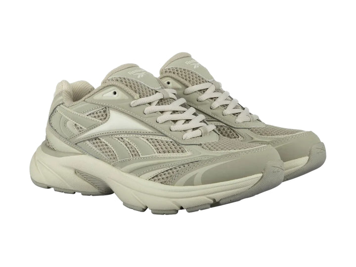 Tenis deportivos Reebok color beige con paneles de malla y suela robusta.