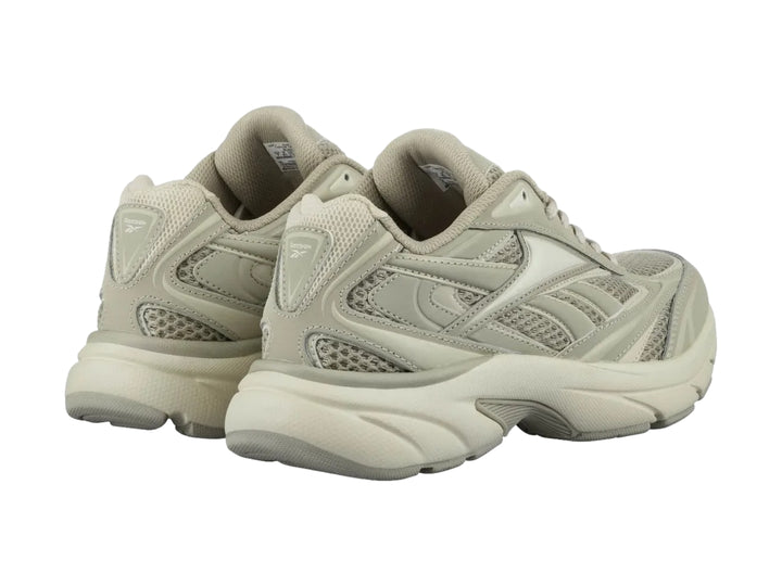 Tenis deportivos Reebok color beige con paneles de malla y suela robusta.