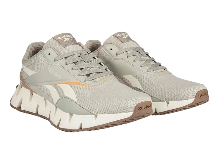 Tenis deportivos Reebok en color gris y blanco con detalles en naranja y suela blanca dentada.
