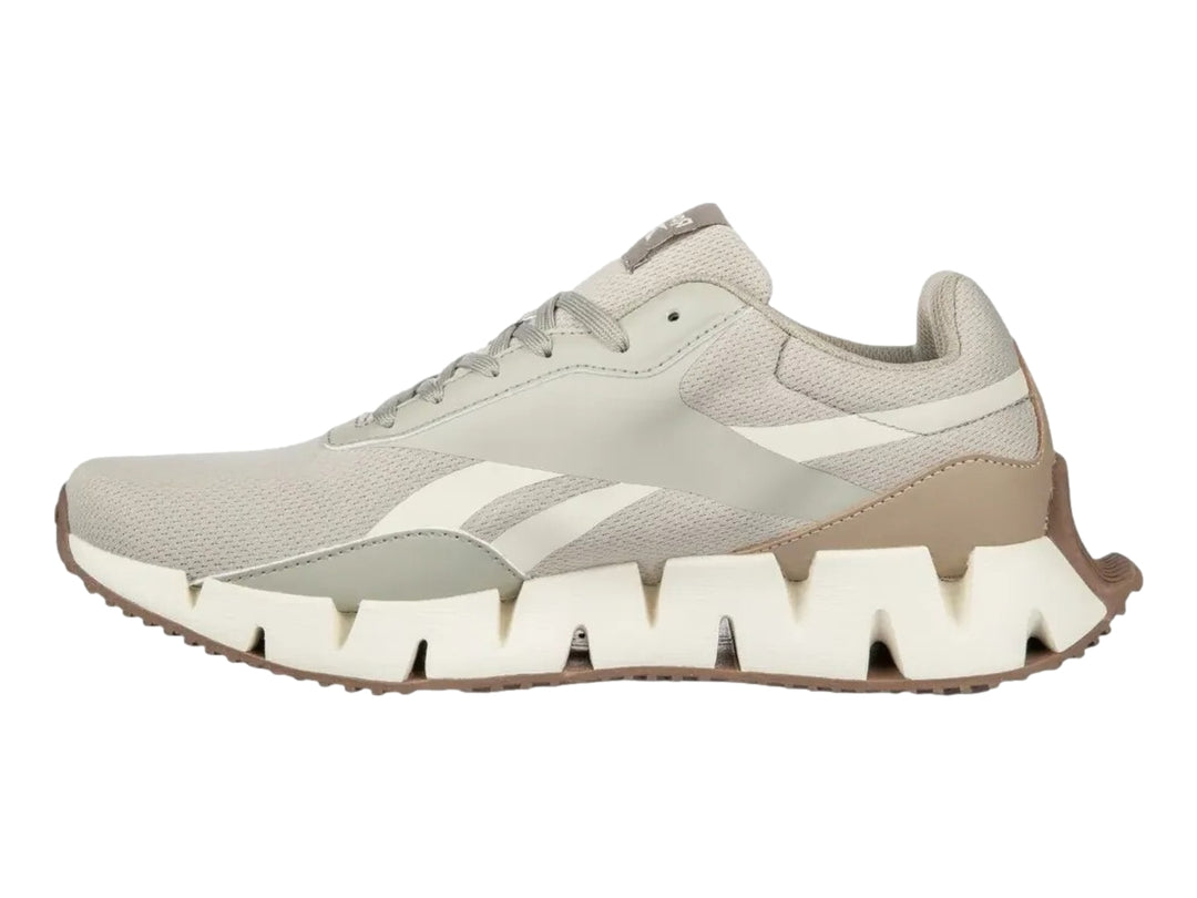 Tenis deportivos Reebok en color gris y blanco con detalles en naranja y suela blanca dentada.