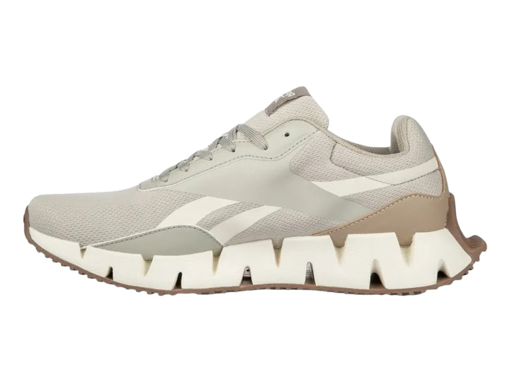 Tenis deportivos Reebok en color gris y blanco con detalles en naranja y suela blanca dentada.