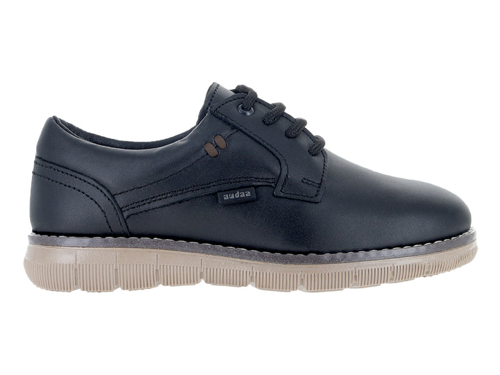 Zapato infantil color negro con cordones y suela gruesa en tono beige.