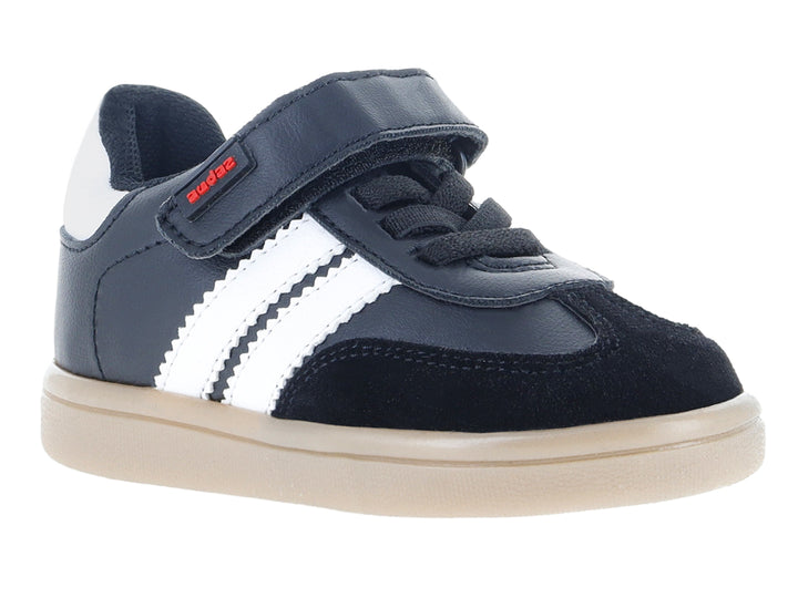 Tenis infantiles color negro con franjas blancas laterales y suela beige.