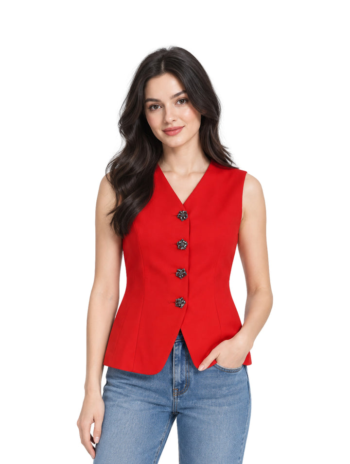 Mujer vistiendo un chaleco rojo entallado con botones negros y pantalones de mezclilla azules.