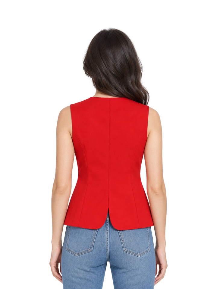 Mujer vistiendo un chaleco rojo entallado con botones negros y pantalones de mezclilla azules.