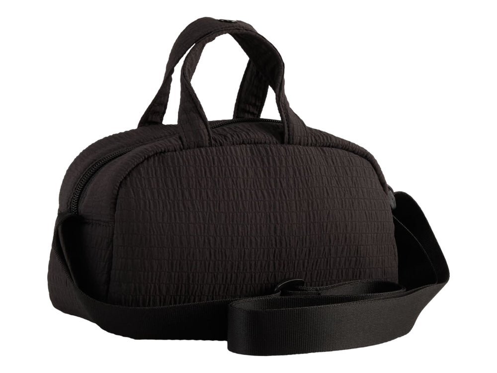 Bolso mini grip PUMA color negro con asas superiores, correa ajustable y logo dorado.