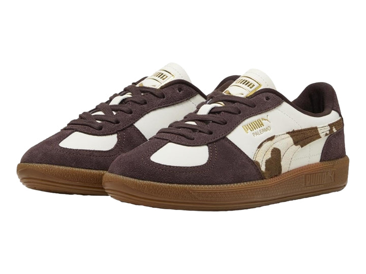 Tenis PUMA Palermo en color blanco y marrón chocolate con estampado de vaca y suela de goma.