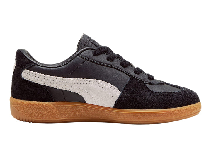 Tenis PUMA Palermo color negro con suela de goma café y franja lateral gris.