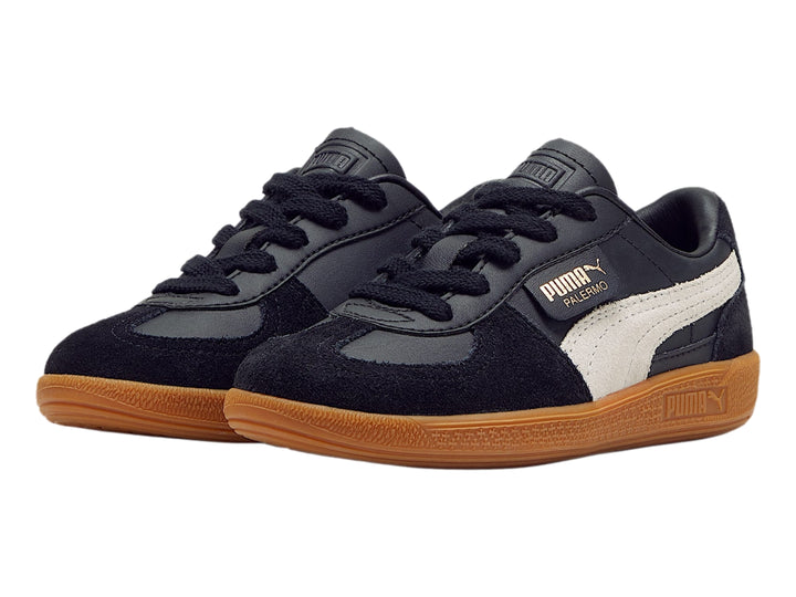 Tenis PUMA Palermo color negro con suela de goma café y franja lateral gris.