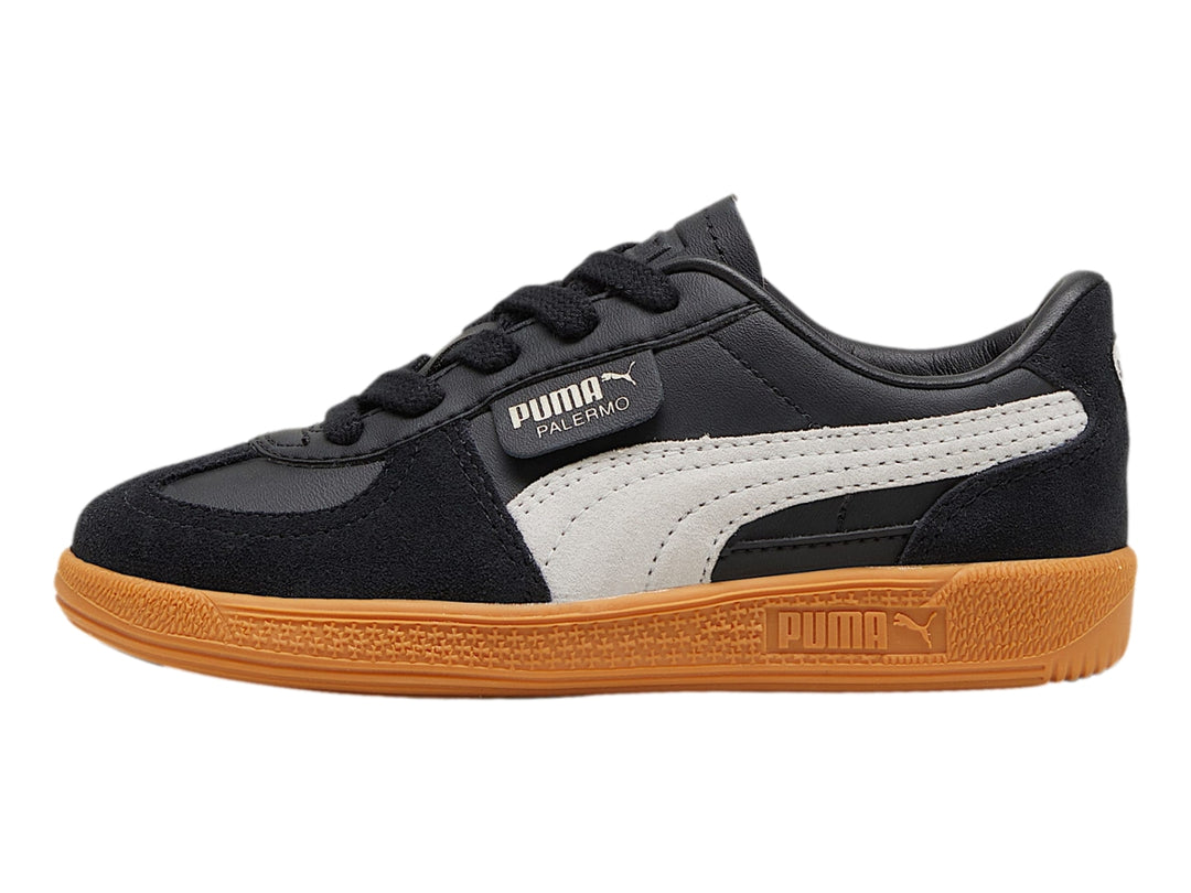 Tenis PUMA Palermo color negro con suela de goma café y franja lateral gris.