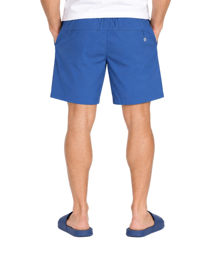 Hombre vistiendo bermuda American Fly color azul medio con cordón ajustable y sandalias azules.