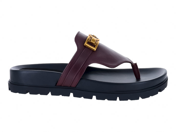 Sandalias Guess color vino con suela negra gruesa y hebilla dorada para mujer.