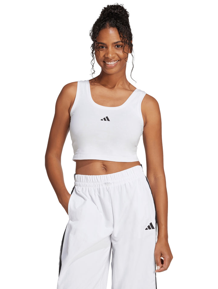 Mujer vistiendo un top corto blanco sin mangas de la marca Adidas.