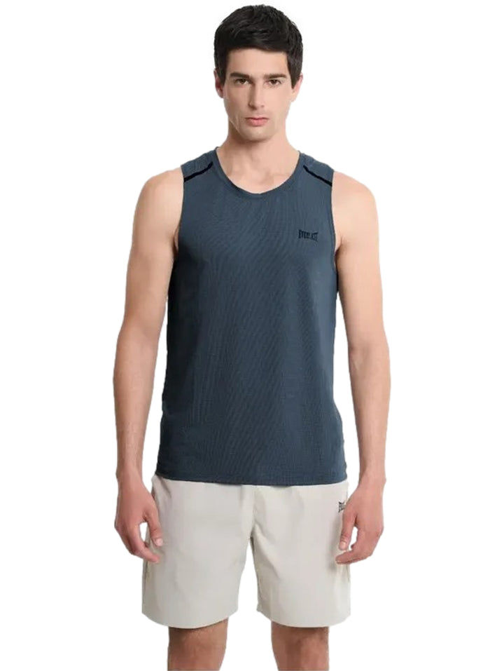 Hombre vistiendo camiseta sin mangas color azul marino y shorts beige.