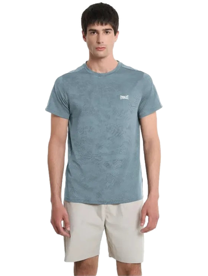 Hombre vistiendo playera deportiva azul de marca Everlast y shorts beige.