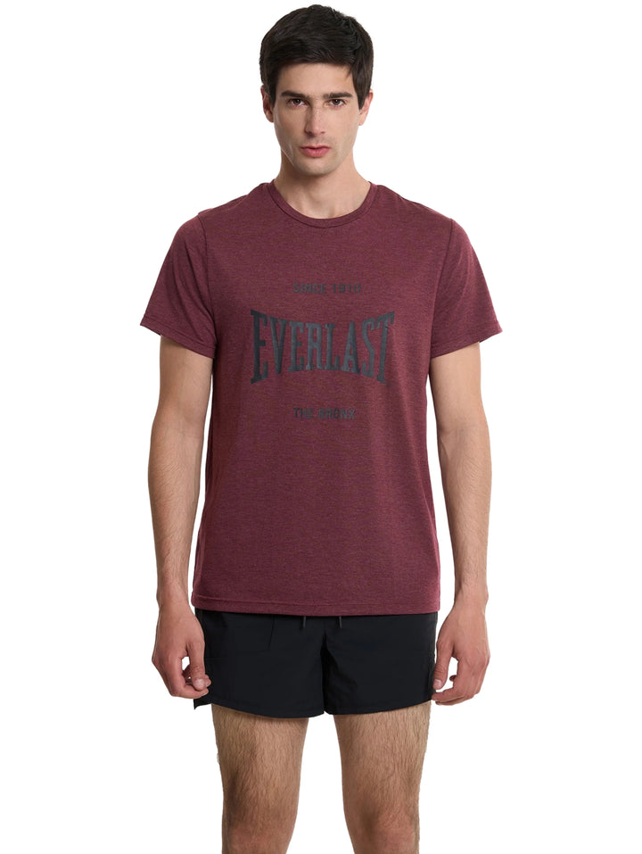 Hombre vistiendo una camiseta deportiva de color rojo oscuro con el logo de Everlast en el pecho.