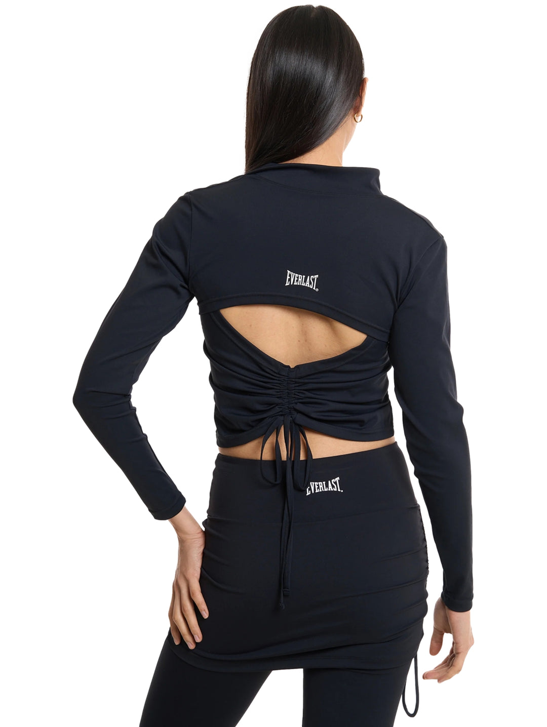 Mujer vistiendo conjunto deportivo Everlast color negro con chaqueta corta y top.