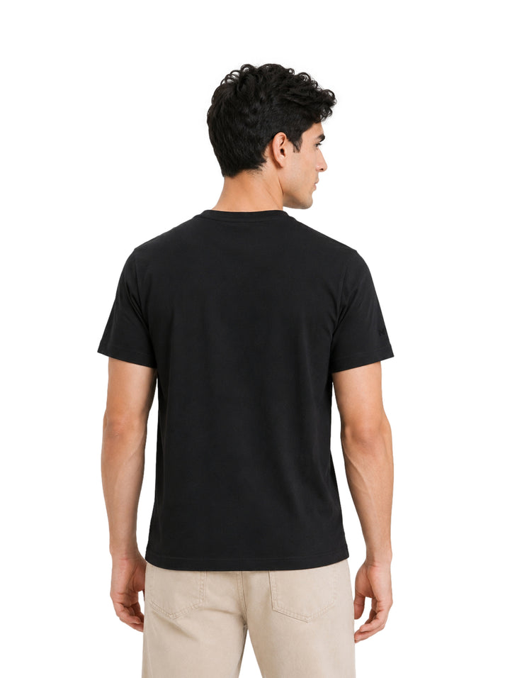 Hombre vistiendo una playera DKNY de color negro con bolsillo frontal y cuello redondo.