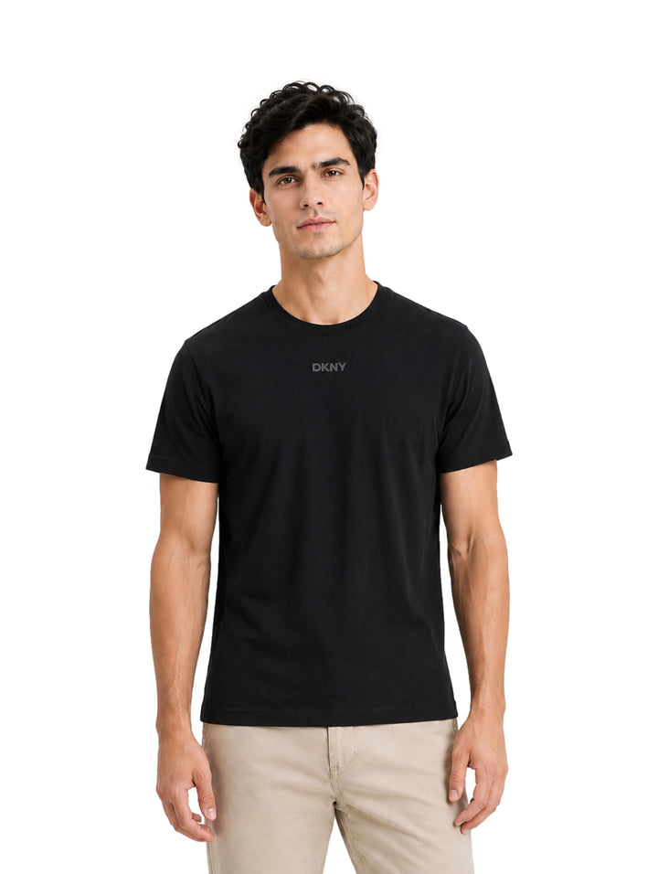 Hombre vistiendo una playera negra de manga corta marca DKNY y pantalones color beige.