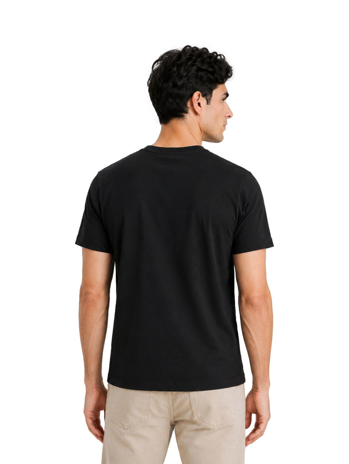 Hombre vistiendo una playera DKNY de color negro con cuello redondo y manga corta.