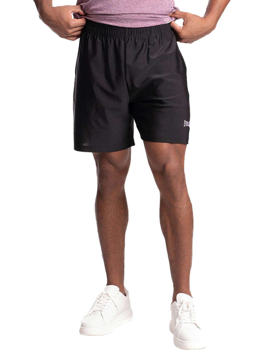Hombre vistiendo shorts deportivos color negro de la marca Everlast y tenis blancos.