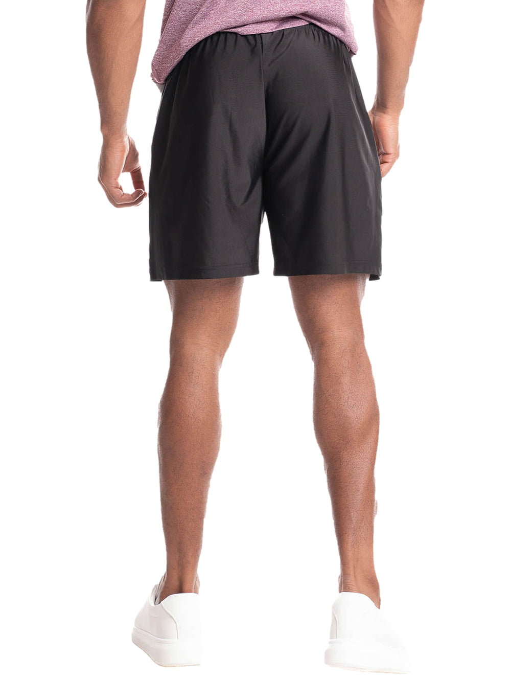 Hombre vistiendo shorts deportivos color negro de la marca Everlast y tenis blancos.