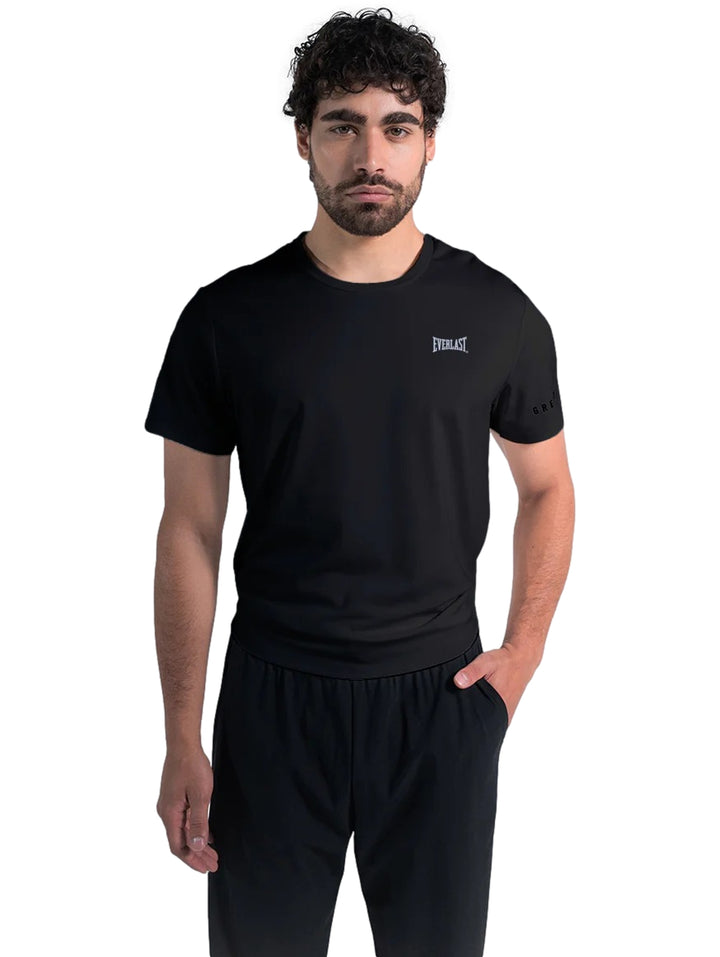 Hombre vistiendo una playera deportiva negra de manga corta marca Everlast y pantalones negros.