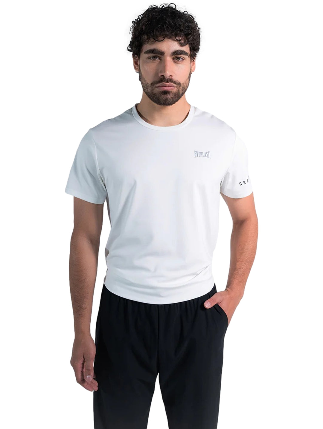 Hombre modelando una playera deportiva blanca de manga corta marca Everlast y pantalones negros.