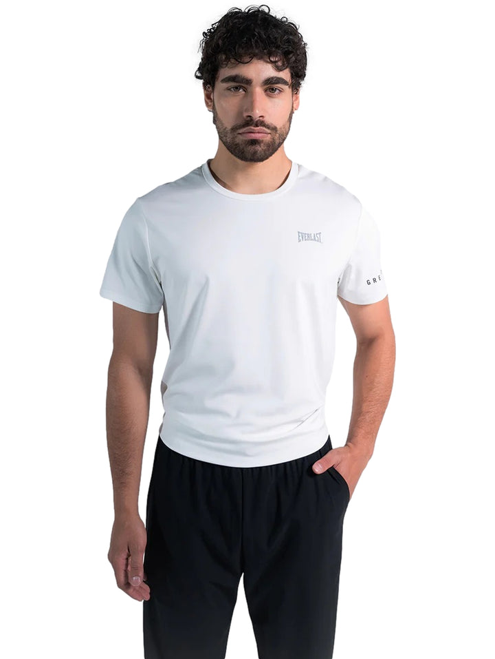 Hombre modelando una playera deportiva blanca de manga corta marca Everlast y pantalones negros.