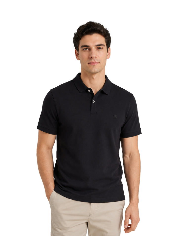 Hombre modelando una playera polo DKNY de color negro con cuello y botones.