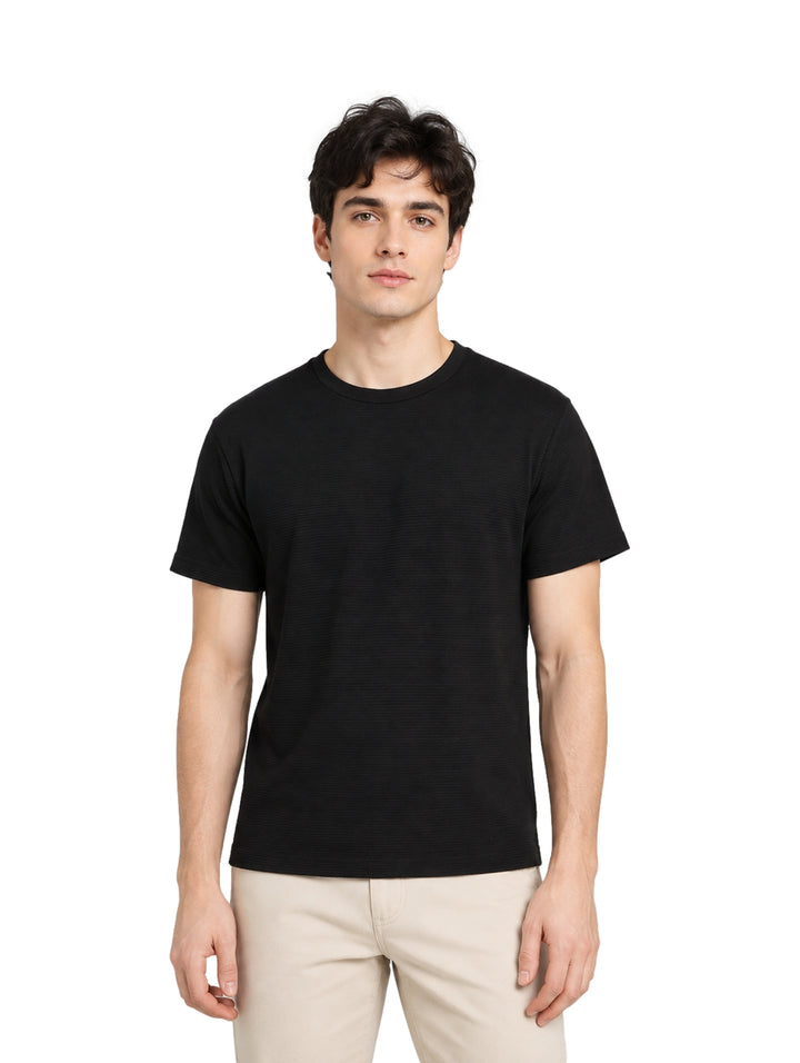Hombre vistiendo una playera DKNY de color negro y manga corta con cuello redondo.