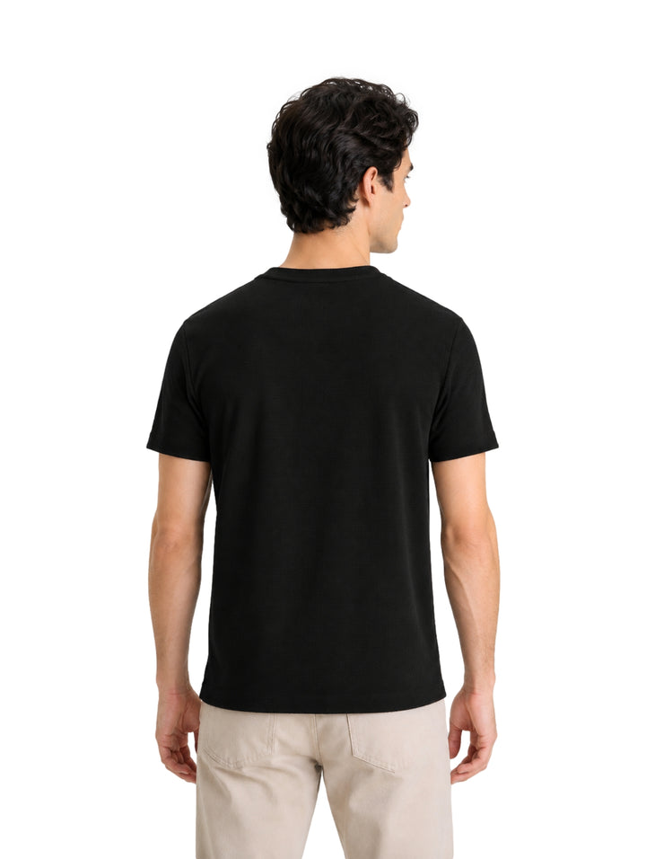 Hombre vistiendo una playera DKNY de color negro y manga corta con cuello redondo.