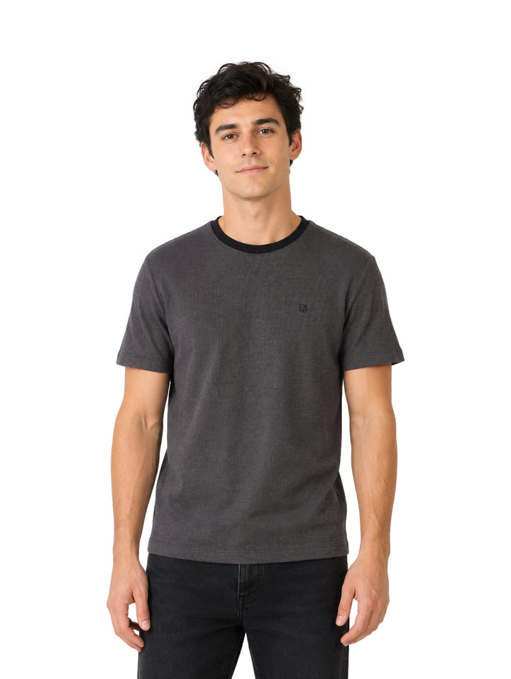 Hombre vistiendo una playera DKNY de color negro con cuello redondo y manga corta.