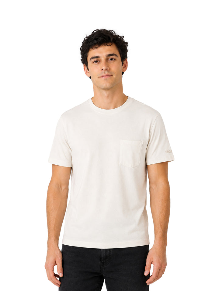 Hombre vistiendo playera DKNY color tofu de manga corta con bolsillo frontal y cuello redondo.