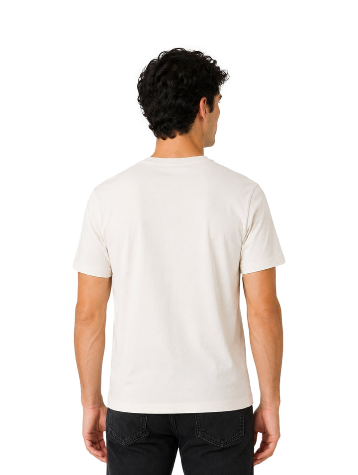 Hombre vistiendo playera DKNY color tofu de manga corta con bolsillo frontal y cuello redondo.