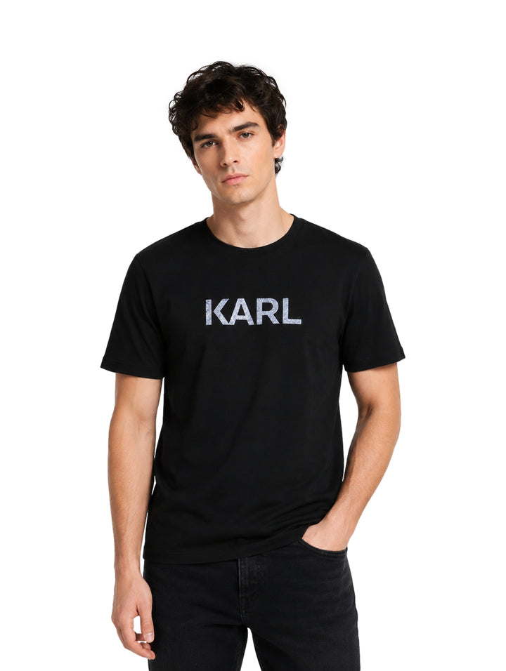 Hombre vistiendo playera negra de manga corta con el texto KARL en el pecho.