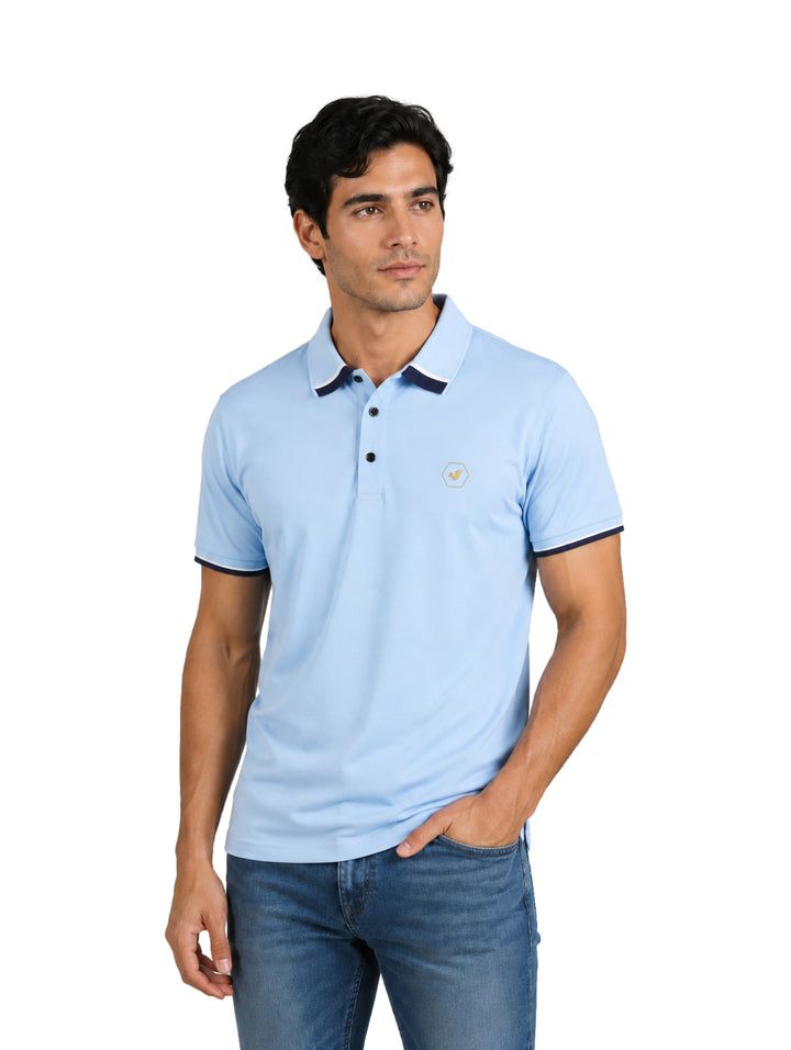 Hombre vistiendo playera polo azul claro con detalles en azul marino en el cuello y mangas.