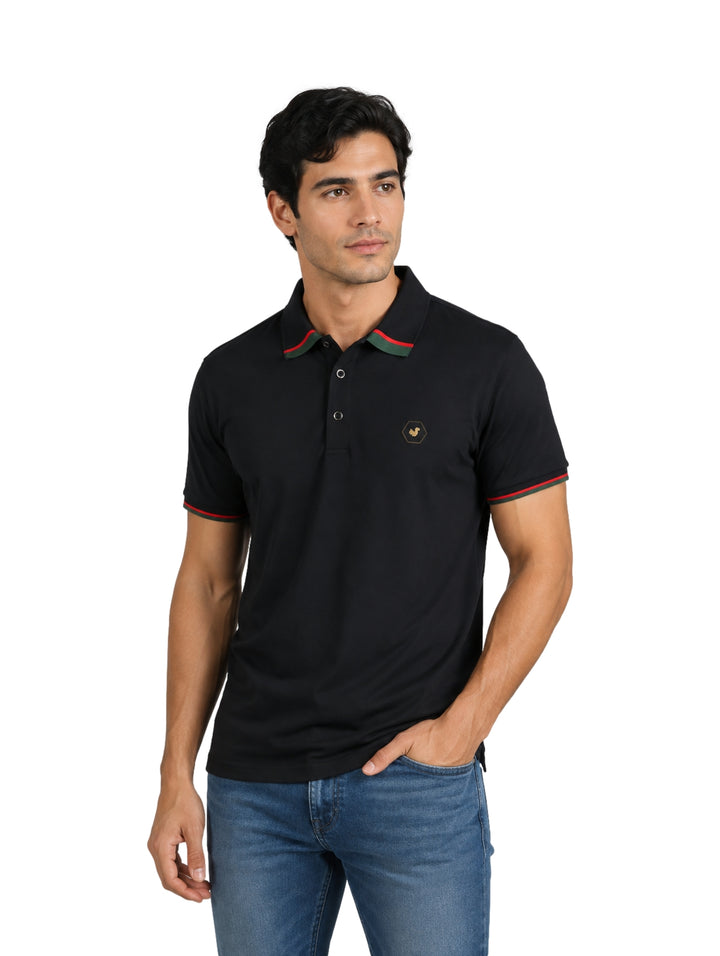 Hombre vistiendo playera polo Pavini color negro con detalles en verde y rojo en el cuello y mangas.