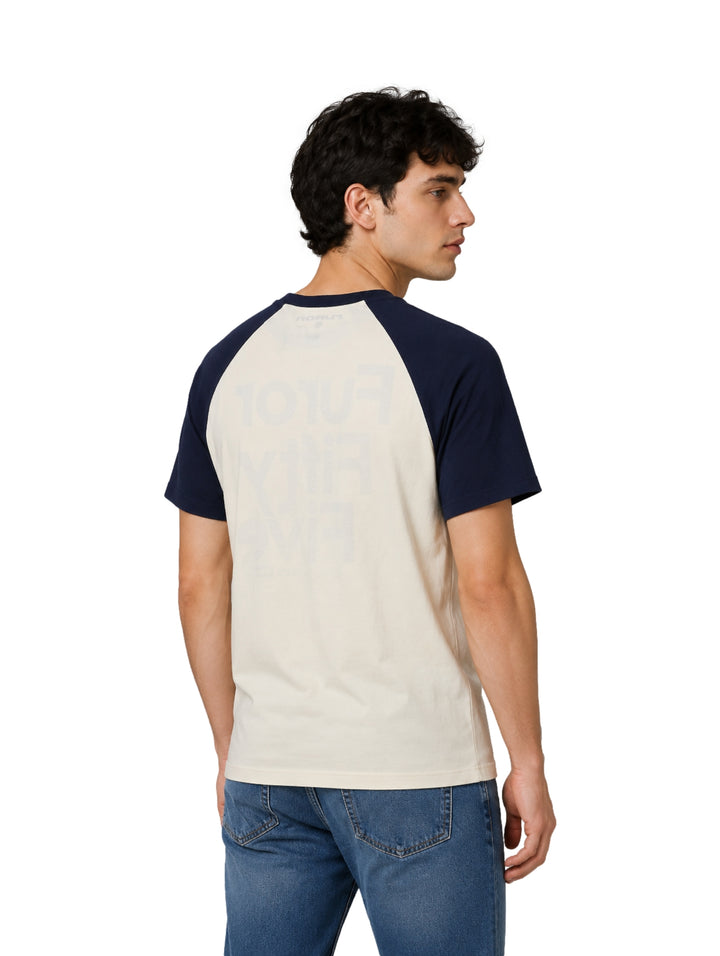 Hombre vistiendo playera raglán color hueso con mangas azul marino y estampado frontal de la marca Furor.
