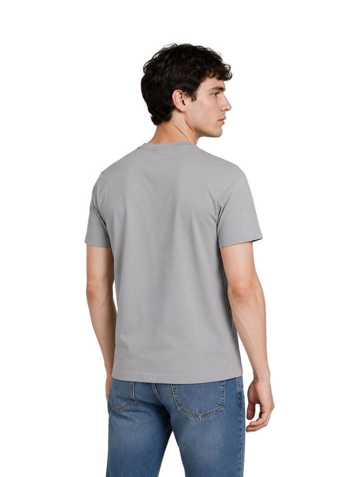 Hombre vistiendo una playera de color gris claro de manga corta y cuello redondo.