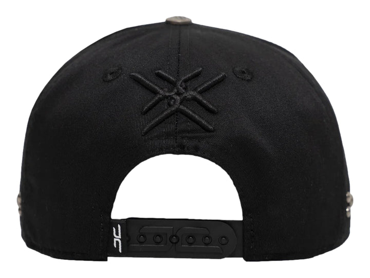 Gorra negra de JC HATS con bordado frontal y detalles metálicos laterales.