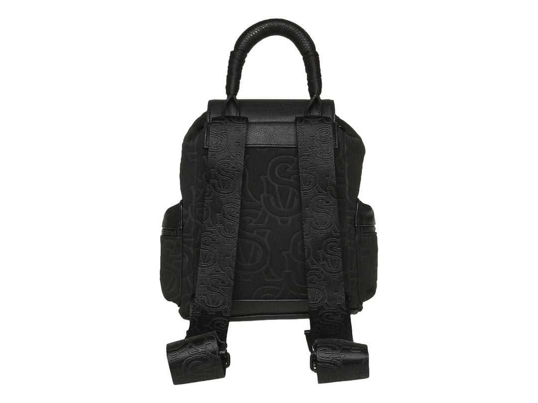 Mochila Steve Madden color negro con estampado monocromático, detalles en piel sintética y asa superior.
