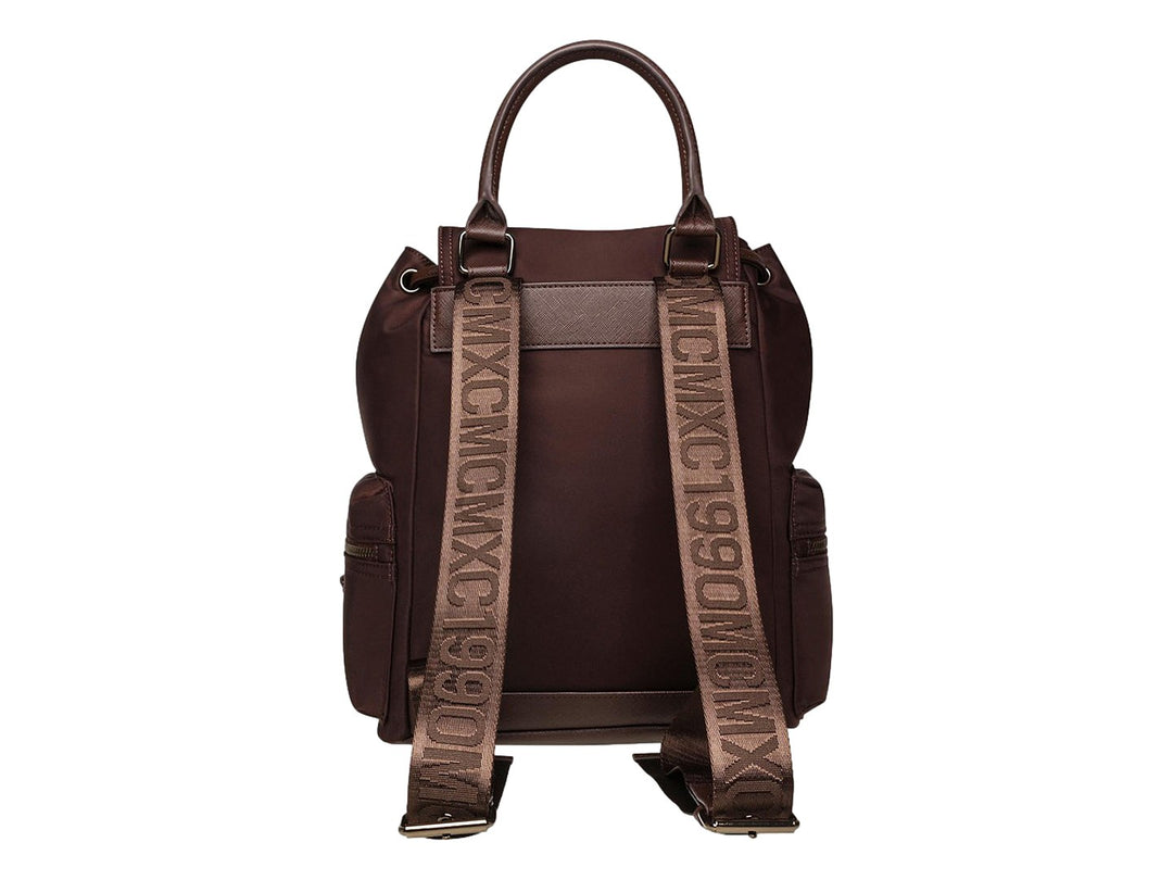 Mochila Steve Madden color café con detalles en bronce, asa superior y bolsillos laterales.